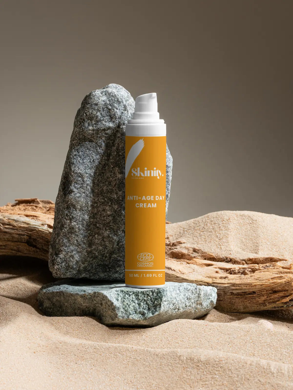 Anti-Age Day Cream For All Skin displayed on natural stones in a serene, sandy background.